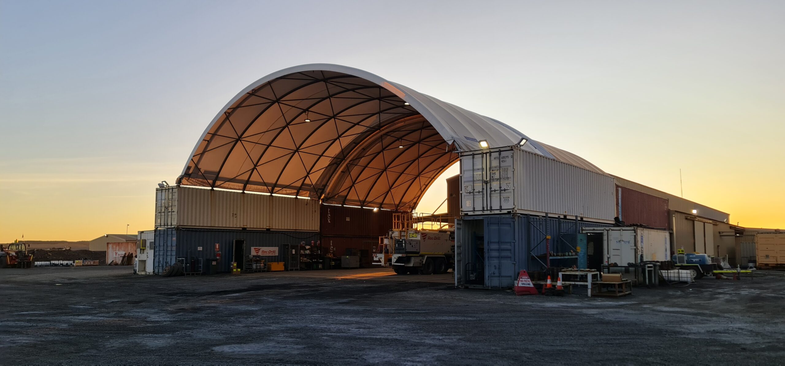 A large dome shelter showcasing heavy machinery parked inside under cloudy skies.