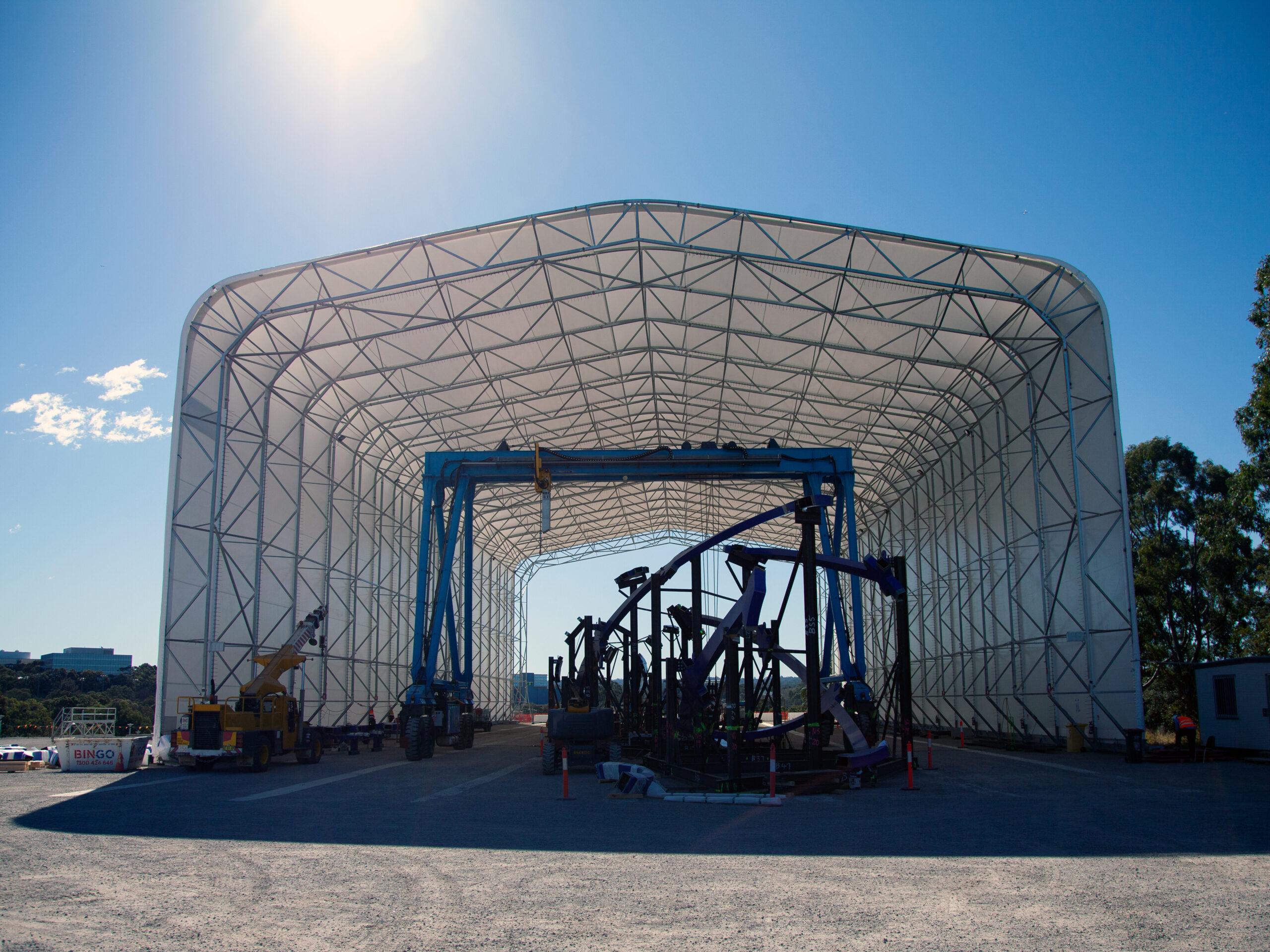 Large industrial equipment housed under a tall fabric dome shelter in an open yard.