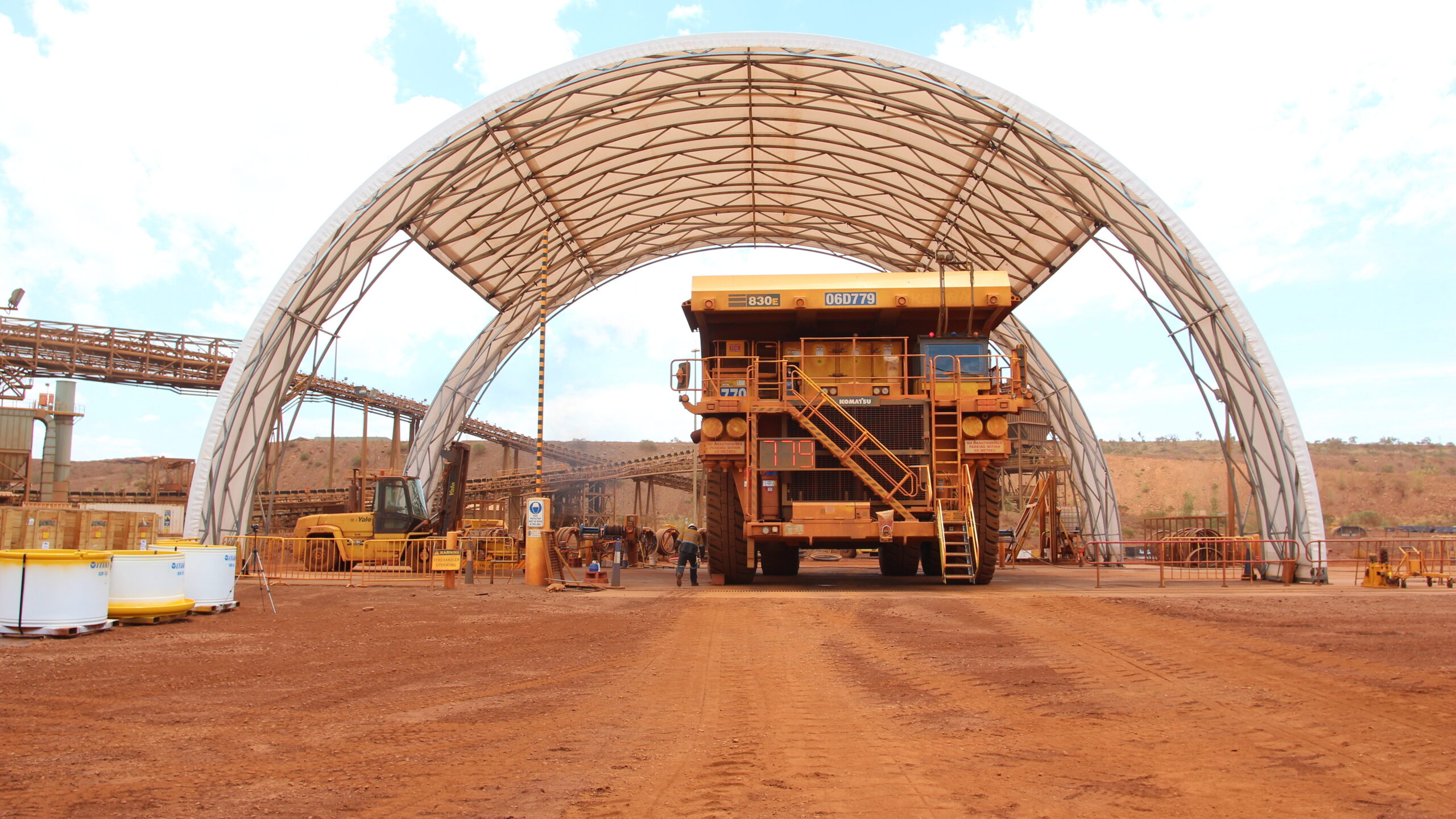 Mining machinery is housed under a spacious dome shelter in a mining operation.